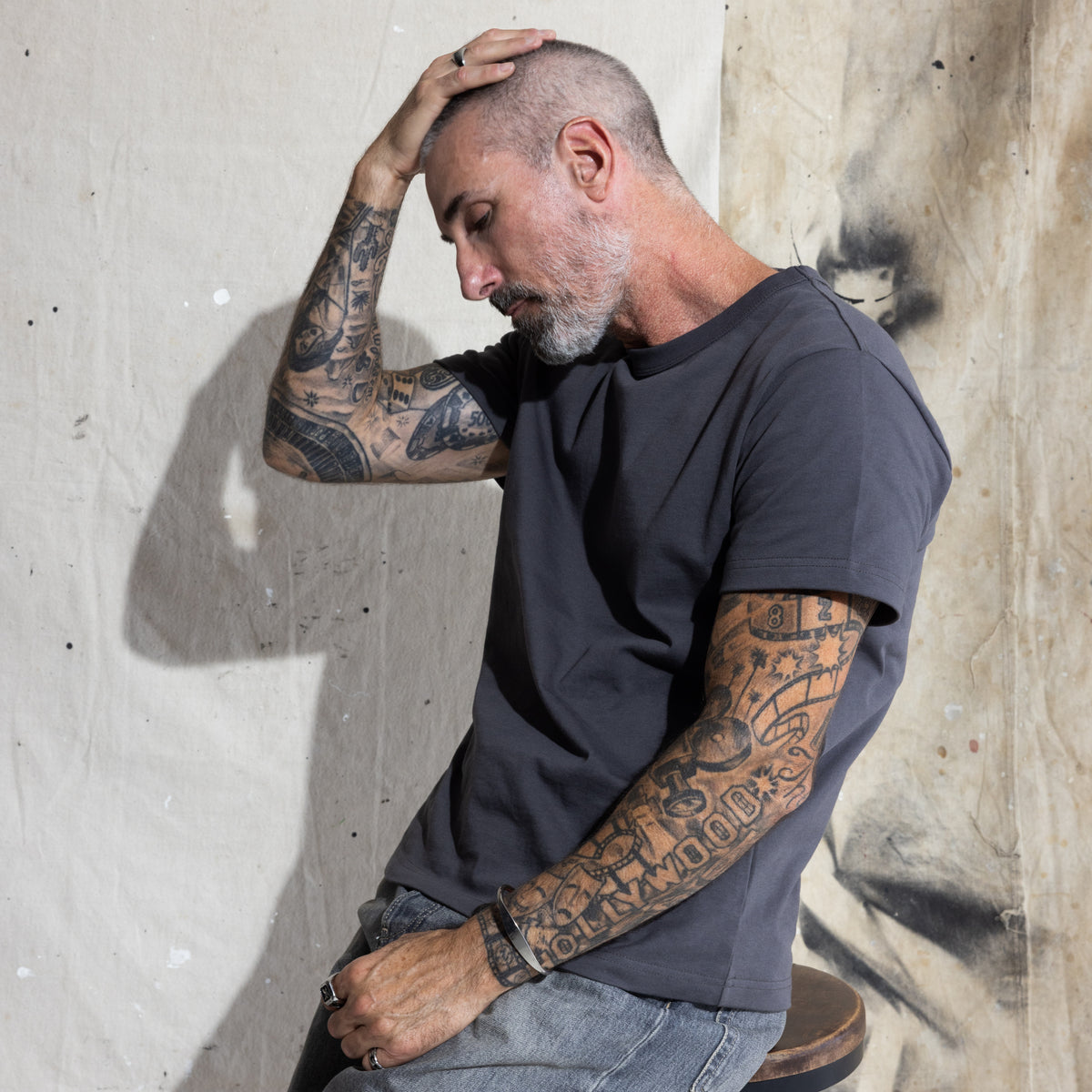 Premium Fitted Heritage Tee in Washed Black, seated on model